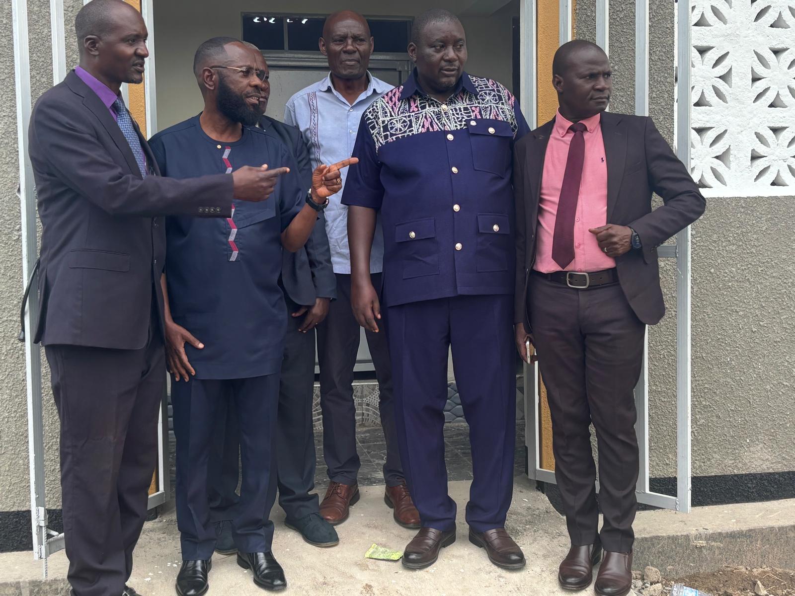 Five officials standing in the doorway of a newly built sanitation facility