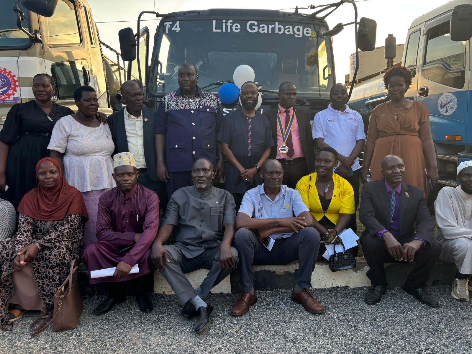Large group of Rotarians, officials and community members photographed in front of the project trucks