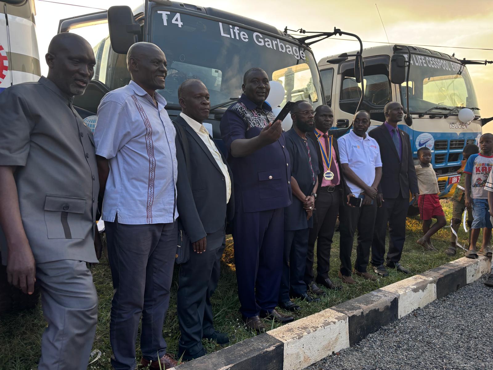 An official addressing attendees in front of the project trucks