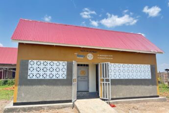 Front view of a completed Toilets 4 Life Phase II sanitation block with a red roof and painted Rotary signage