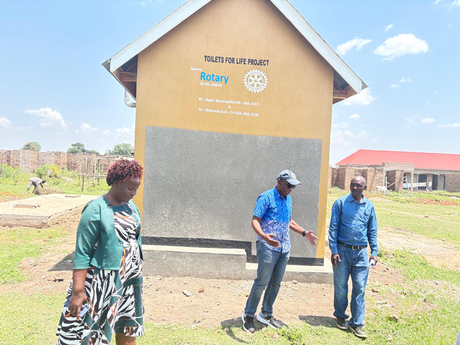 Visitors standing beside the gable end of a completed sanitation facility