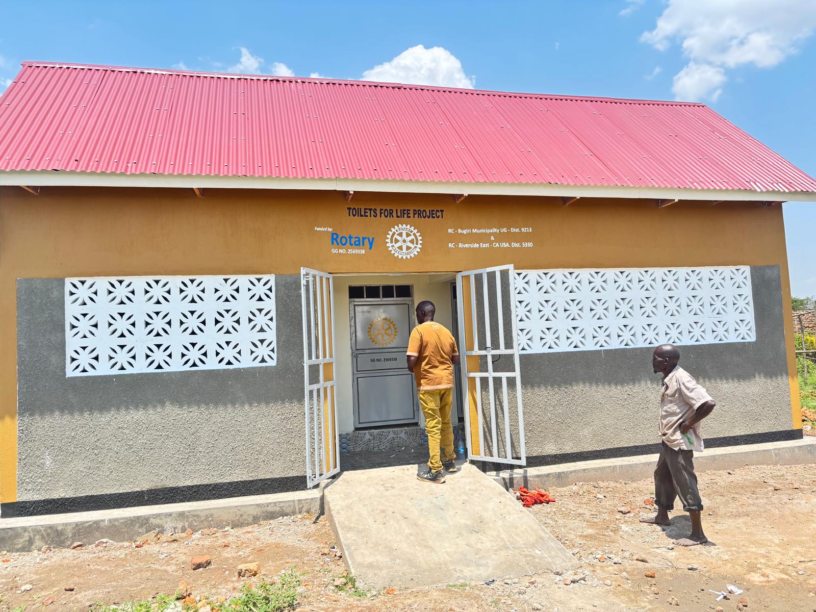 A man entering the doorway of a completed Toilets 4 Life sanitation facility